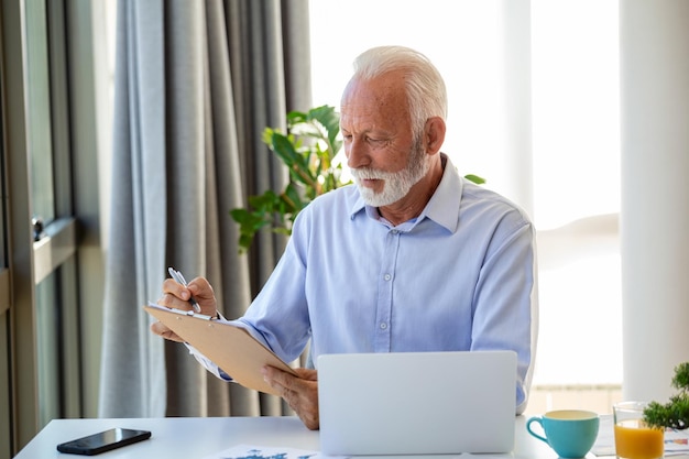 Homme d'affaires senior concentré présentant des tableaux et des graphiques lors d'un appel vidéo en ligne Homme d'affaires mature ayant une conférence téléphonique avec un client sur un ordinateur portable expliquant le fonctionnement de l'entreprise