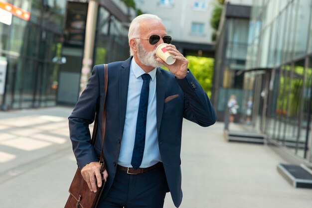 Homme d'affaires senior marchant et buvant du café