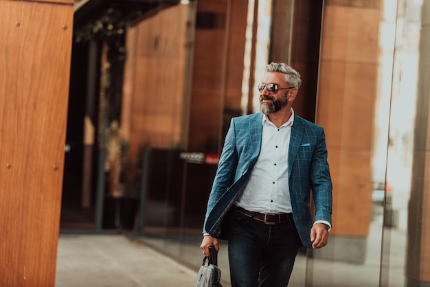 Un homme d'affaires senior moderne avec un sac quitte une société moderne