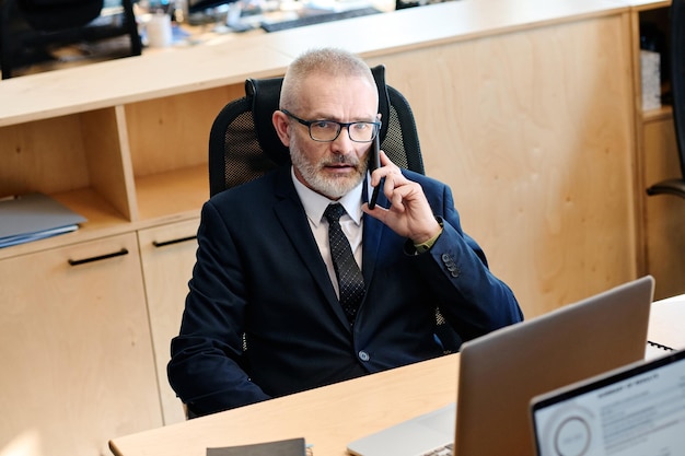 Homme d'affaires senior parlant au téléphone au bureau