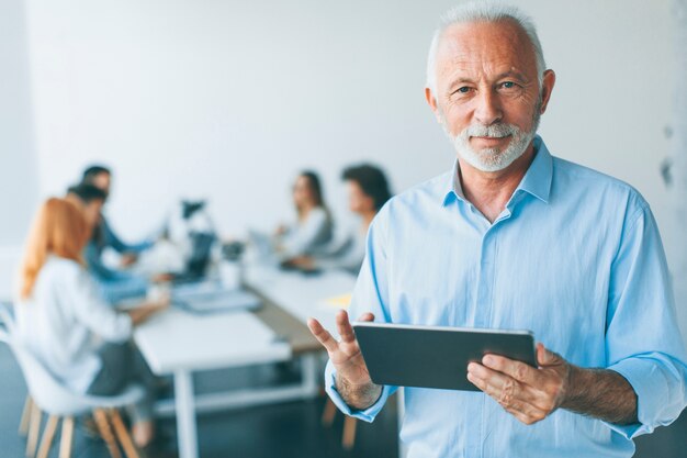 Homme d&#39;affaires senior permanent avec tablette numérique à la main