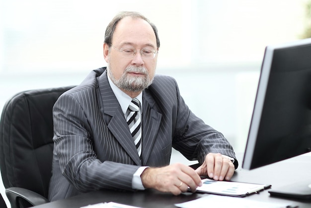 Homme d'affaires senior prospère assis à son bureau