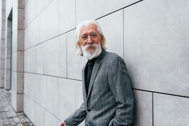 Un homme d'affaires senior en vêtements formels aux cheveux gris et à la barbe est à l'extérieur