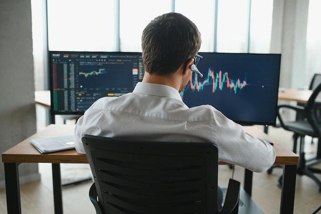 Homme d'affaires sérieux analyste commerçant regardant un écran d'ordinateur courtier investisseur analysant des indices tableau financier négociant des données d'investissement en ligne sur le graphique du marché boursier de crypto-monnaie sur l'écran de l'ordinateur