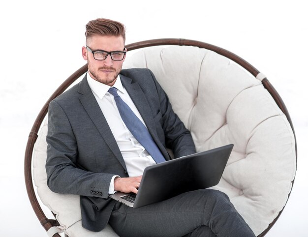 Homme d'affaires sérieux avec un ordinateur portable assis sur une chaise