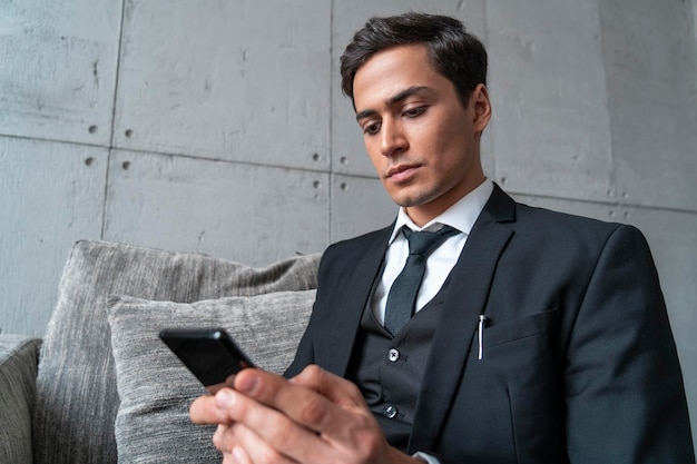 Homme d'affaires sérieux utilisant le téléphone dans le fauteuil