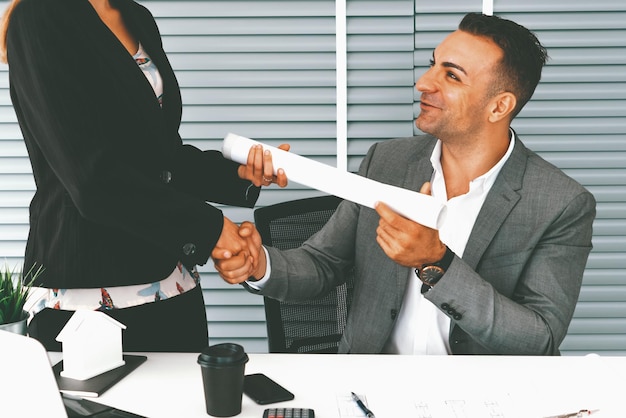 Un homme d'affaires serre la main d'une femme d'affaires dans un bureau.