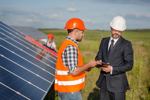 Homme d&#39;affaires signant un contrat avec contremaître, technicien examinant des panneaux solaires