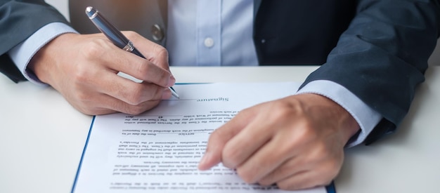 Homme d'affaires signant des documents contractuels après avoir lu un homme tenant un stylo et approuvé le rapport d'activité Accord de contrat de partenariat et de concepts d'accord