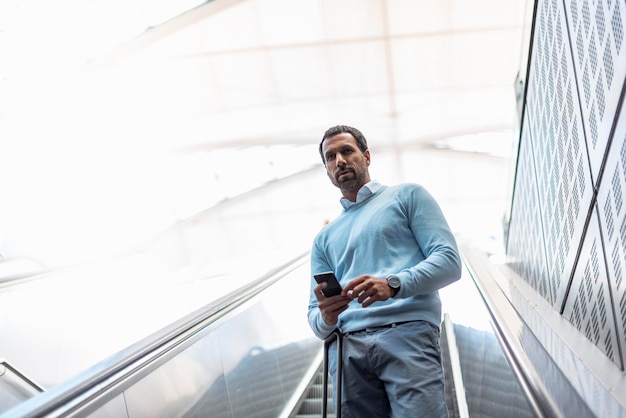 Homme d'affaires avec smartphone sur escalator