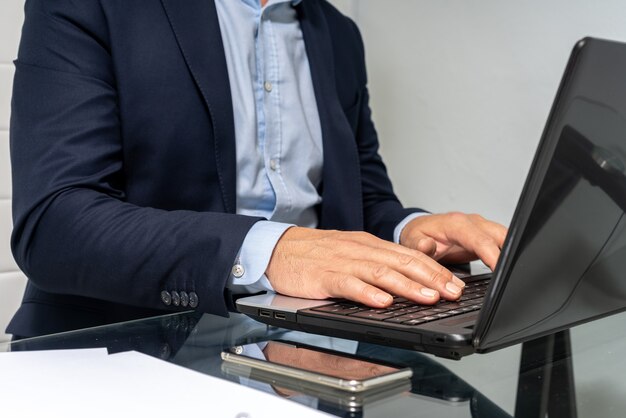 Photo homme d'affaires à son bureau travaillant sur l'ordinateur se concentrer sur les mains