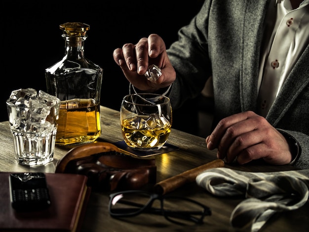 Photo un homme d'affaires soulage le stress après une dure journée de travail en buvant du whisky et met un glaçon dans son verre