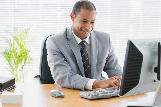 Homme d&#39;affaires souriant à l&#39;aide d&#39;ordinateur au bureau