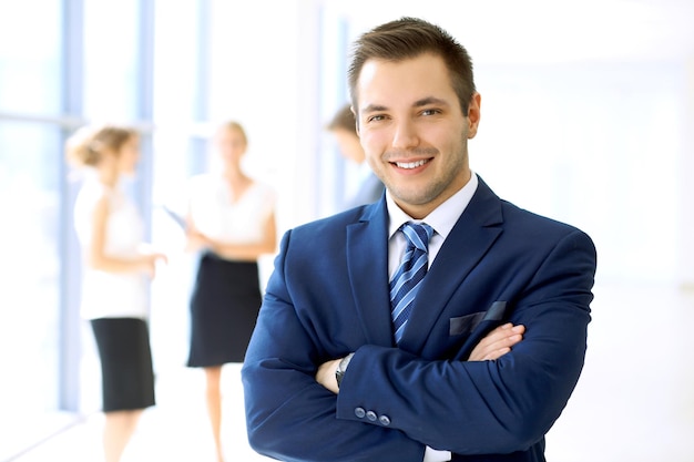 Homme d'affaires souriant au bureau avec des collègues en arrière-plan