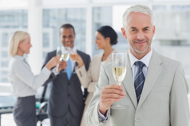 Homme d&#39;affaires, souriant à la caméra, tenant le champagne