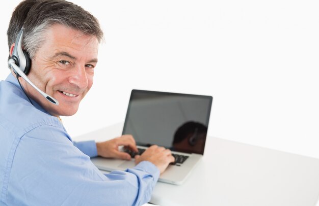 Homme d&#39;affaires souriant avec casque travaillant sur ordinateur portable