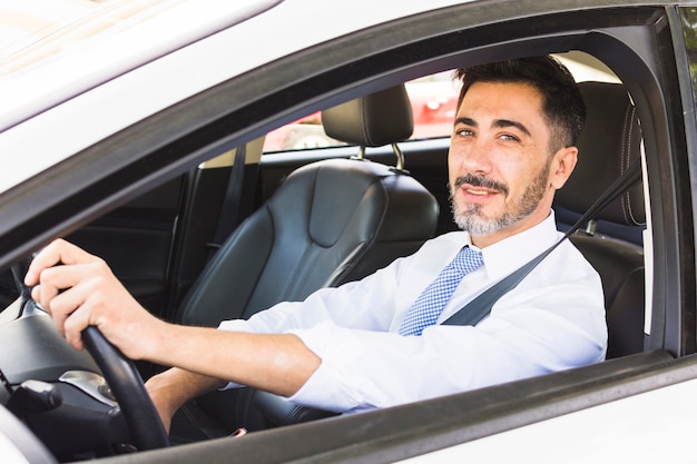 Homme d&#39;affaires souriant confiant, regardant la caméra en conduisant la voiture