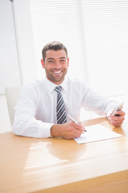 Homme d&#39;affaires souriant écrit à son bureau