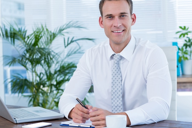 Homme d&#39;affaires souriant, écrivant sur ordinateur portable