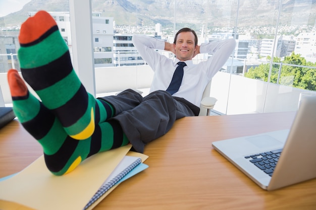 Homme d&#39;affaires souriant faire une sieste avec les pieds sur le bureau