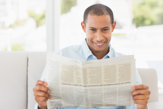 Homme d&#39;affaires souriant, lisant un journal sur le canapé