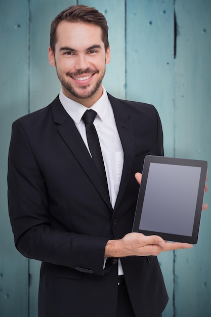 Homme d'affaires souriant montrant son tablet pc contre des planches de bois peintes en bleu