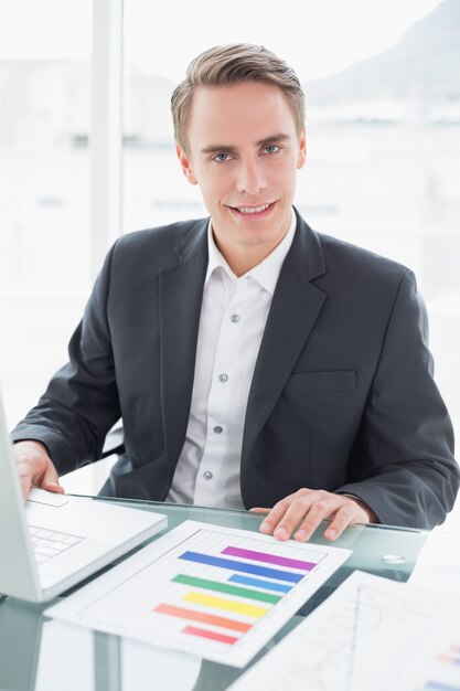 Homme d&#39;affaires souriant avec ordinateur portable au bureau