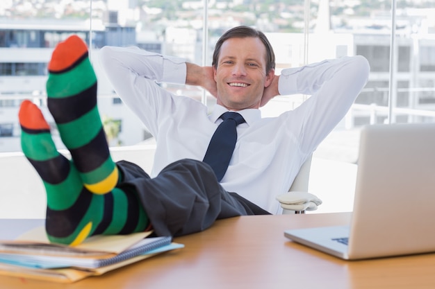 Homme d&#39;affaires souriant se détendre avec les pieds sur son bureau