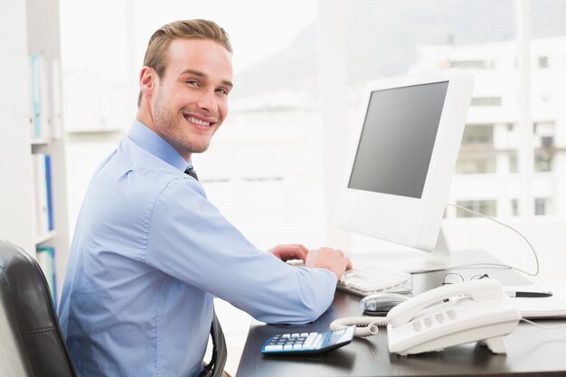 Homme d&#39;affaires souriant, tapant sur le clavier au bureau