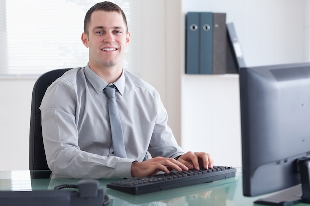 Homme d&#39;affaires souriant, tapant sur son ordinateur