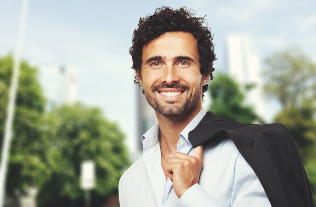 Homme d&#39;affaires souriant tenant sa veste en plein air