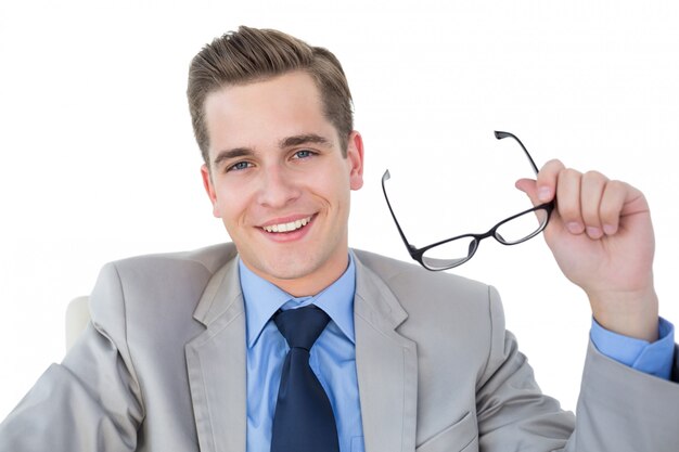 Homme d&#39;affaires souriant tenant ses lunettes sur fond blanc