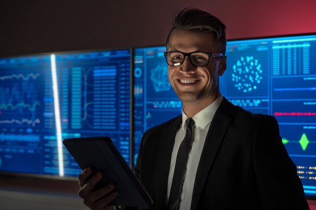 L'homme d'affaires souriant tenant une tablette dans le laboratoire rouge