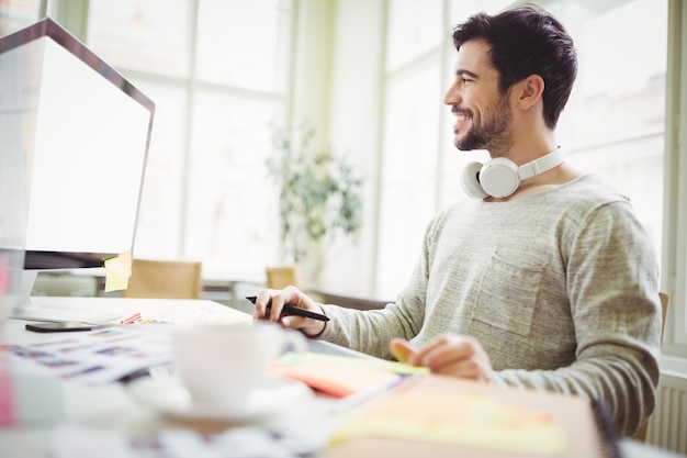 Homme d'affaires souriant travaillant sur ordinateur au bureau