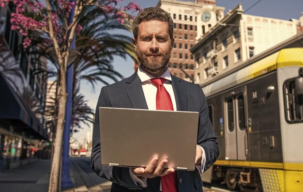 Homme d'affaires souriant utilisant un ordinateur portable pour bloguer sur un réseau social et un blog