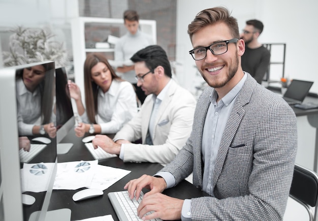 Un homme d'affaires souriant utilise un ordinateur pour analyser des données financières