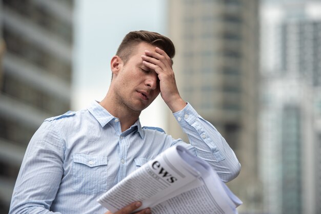 Homme d'affaires stress avec journal s'inquiète des nouvelles du marché boursier.