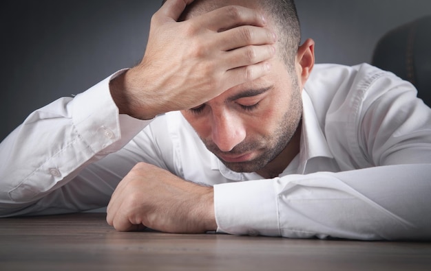 Homme d'affaires stressé caucasien assis au bureau.