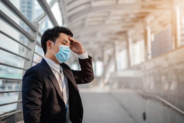 Homme d'affaires stressé avec masque médical pendant la pandémie de coronavirus dans la ville