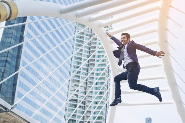 L'homme d'affaires de style de vie se sent heureux de sauter dans l'air pour célébrer le succès et la réussite sur le concept d'entreprise du quartier des affaires