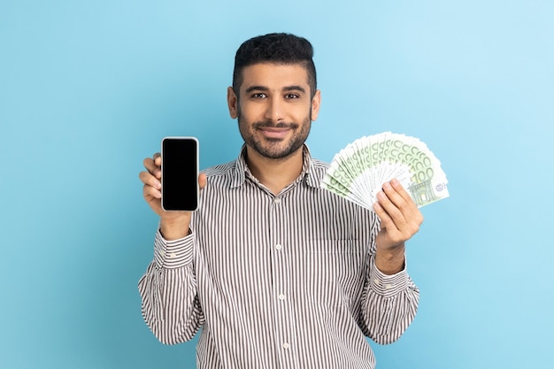 Homme d'affaires surpris avec barbe tenant un téléphone portable et des billets en euros choqué par le cashback en argent