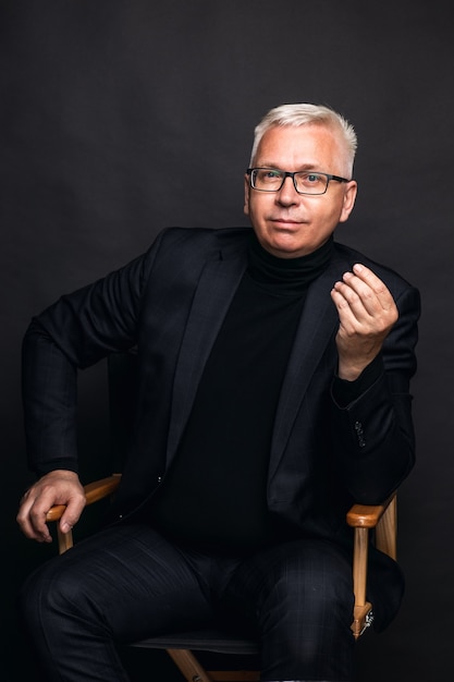 Homme D'affaires Sympathique Portant Des Lunettes Et Un Costume Posant Avec Souriant à La Caméra Sur Un Fond De Studio Noir Avec Espace Copie