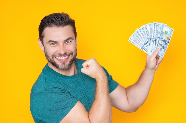 Homme d'affaires en t-shirt avec de l'argent en espèces billets en dollars isolés sur fond de studio jaune hundre