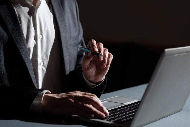 Homme d'affaires tapant un concept important dans un ordinateur portable et pointant une nouvelle idée avec un stylo Homme en costume écrivant des messages cruciaux sur un clavier d'ordinateur