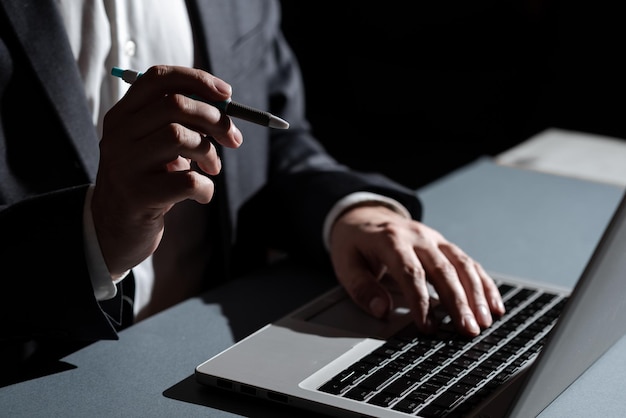 Homme d'affaires tapant un concept important sur un ordinateur portable et pointant une nouvelle idée avec un stylo homme en costume