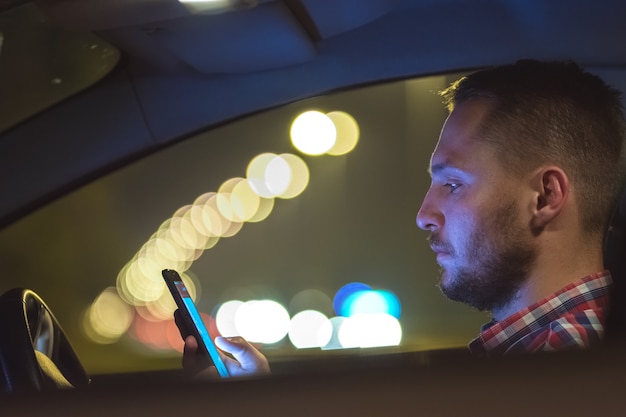 L'homme d'affaires téléphone à l'intérieur de la voiture sur l'autoroute. le soir la nuit