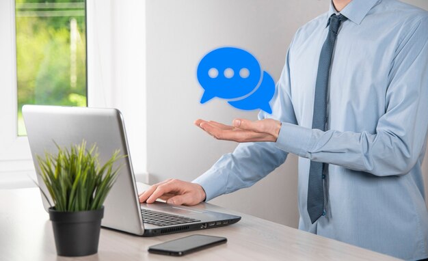 Homme d'affaires tenant une icône de message, signe de notification de conversation de bulle dans ses mains. Icône de chat, icône sms, icône de commentaires, bulles de dialogue