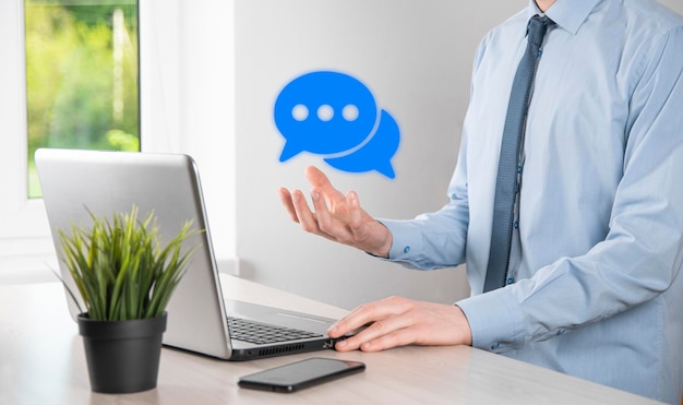 Homme d'affaires tenant une icône de message, signe de notification de conversation de bulle dans ses mains. Icône de chat, icône sms, icône de commentaires, bulles de dialogue.