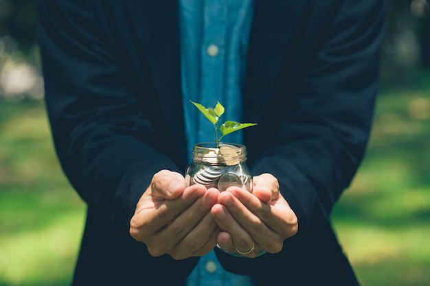 Photo homme d'affaires tenant des jarres de verre avec des plantes qui poussent à partir d'investissements monétaires et financiers eco affaires