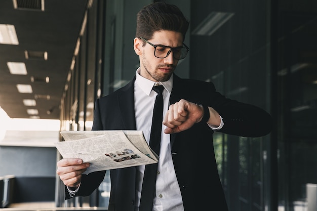 Homme d'affaires tenant le journal en regardant l'horloge de la montre.